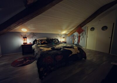 Chambre mansardée avec lit et décor asiatique